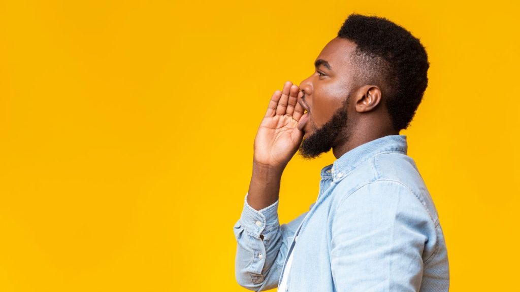 man trying to speak to an audience with yellow background
